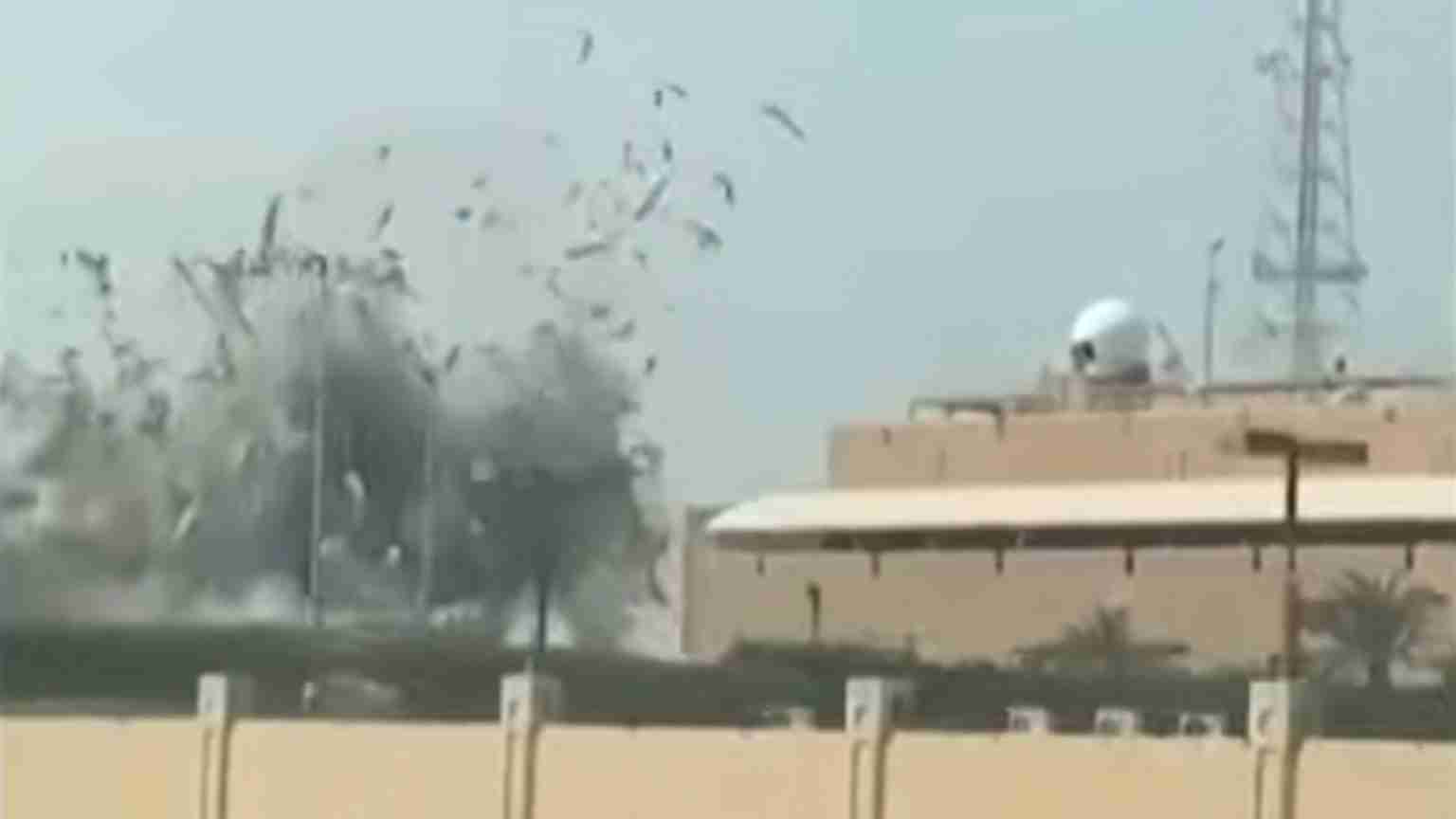 Explosion or blast near a tan military building with a domed radar on the roof and debris in the air