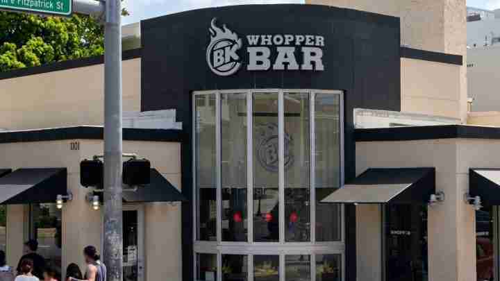 Whopper Bar storefront with tall curved glass entrance, black facade, and BK logo above the door.