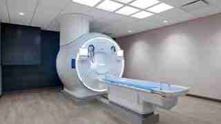 MRI scanner with a circular bore and an adjustable patient table in a clinical imaging room