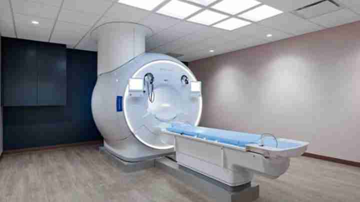 MRI scanner with a circular bore and an adjustable patient table in a clinical imaging room