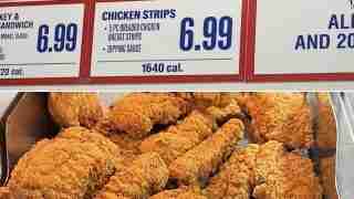 Cripsy fried chicken pieces in a display case with menu boards showing chicken strips for $6.99 and 1640 cal.