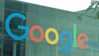 Google logo in blue, red, yellow, and green on a glass office building facade