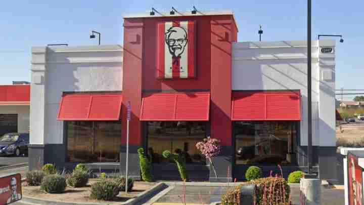 KFC restaurant with red exterior, large Colonel Sanders sign above the entrance, and red awnings.