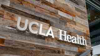 Wood-clad wall with large UCLA Health signage in white letters on rustic planks