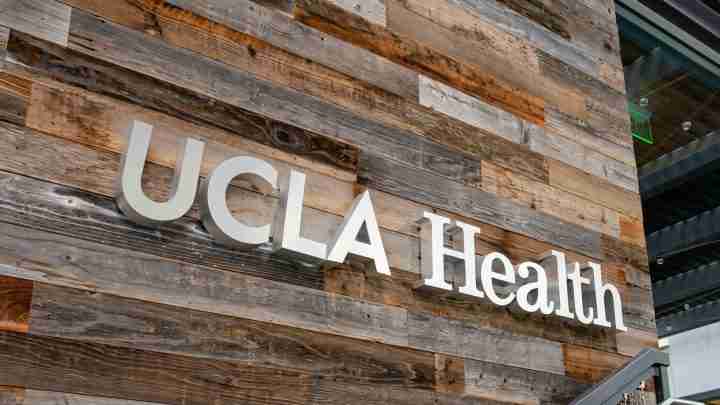 Wood-clad wall with large UCLA Health signage in white letters on rustic planks
